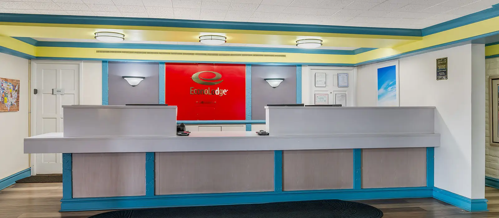 The hotel reception area features a long grey and wood-panelled counter with a red EconoLodge sign behind it