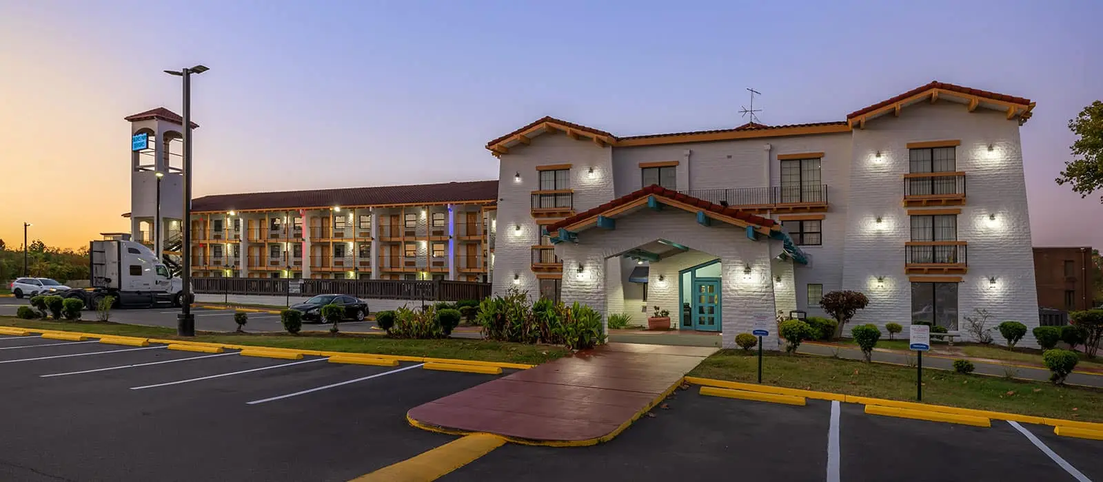 The Econo Lodge Richmond exterior at dusk, lit against an evening sky, with the parking lot in the foreground